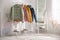 Different warm jackets on rack in stylish room interior