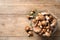 Different wild mushrooms in metal basket on wooden background, top view