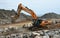 Digger moving large boulders on construction site.