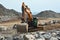 Digger moving large boulders on construction site.