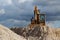 A digger on top of a gravel dune