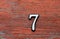 Digit 7 on red shabby wooden wall, close-up