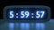 Digital alarm clock with blue clockface waking up at 6 AM. The numbers on the clock screen changes from 5:55 to 6:00 AM