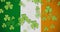 Digital animation of multiple clover leaves floating against irish flag