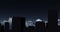 Digital animation of silhouette of tall buildings against clouds in night sky