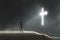 A digital art concept of a hooded figure looking at a glowing cross on a misty, atmospheric night.