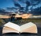 Digital composite concept image of open book wth Abandoned fishing boat on beach landscape at sunset