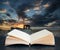 Digital composite image of Abandoned fishing boat on beach landscape at sunset coming out of pages in book