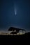 Digital composite image of Neowise Comet over Derelict barn silhouette against beautiful vibrant sunset landscape