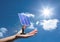 Digital composite image of solar panel on hand against sky