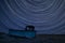 Digital composite image of star trails around Polaris with Abandoned fishing boat on beach landscape