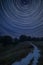 Digital composite image of star trails around Polaris with Stunning inspirational Summer landscape image over English countryside