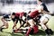 Digital composite image of team of rugby players tackling each other to win the ball in sports stadi