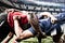Digital composite image of two rugby players tackling each other in sports stadium