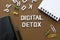 Digital detox word with smart phone, note book, office suplies over brown background