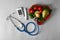 Digital glucometer with lancet pen, stethoscope and healthy food on grey background. Diabetes diet