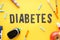 Digital glucometer, lancet pens, syringes and fruits on yellow background close-up. Flat lay