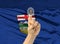 Digital ID Alberta on finger of white skin person and Canadian province flag on background