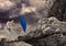 Digital image of rocks falling on businesswoman with blue umbrella standing against sky