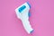 Digital medical infrared forehead electronic thermometer gun non-contact for measuring temperature. Pink background. Coronavirus