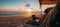 A digital nomad in the sands of a beach with a notebook working in the sunset, sitting close to the shoreline, sun, sky, horizon