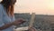 Digital nomad woman working with laptop and mobile phone on the beach by the sea during sunset. Female freelancer work