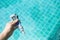 Digital water tester in girl hand over blurred blue swimming pool water background