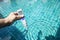 Digital water testing in girl hand over blue swimming pool water background