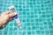 Digital water testing in girl hand over blurred clear swimming pool water