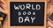 Digitally generated image of world book day text on slate by art equipment on table