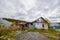 A dilapidated abandoned house in the countryside. There are signs of fire, desolation and old junk