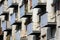 Dilapidated blue concrete and yellow metal pipes fences on multiple balconies on side of large old apartment building