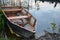 A dilapidated boat moored on the river bank by an iron chain.