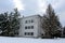 Dilapidated building with tall snow covered trees