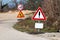 Dilapidated heavily used warning and road under construction with 30 speed limit road signs mounted on metal poles