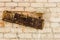 Dilapidated name plate falling from brick wall