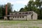 Dilapidated old military barrack with broken windows and missing doors next to tall red brick chimney at abandoned military