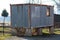 Dilapidated partially rusted metal shipping container converted into living area put on six concrete pillars foundation