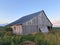 Dilapidated Wooden Barn in a Field in Illinois on a Summer Evening, with blue sky. The black roof is two-sided