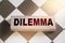 DILEMMA word written on wooden block put on chess board. Yes or no question concept