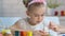 Diligent girl carefully putting pattern with paints on egg, Easter decoration