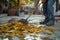 Diligent man with broom tidies cement patio, leaves dancing away