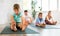 Diligent preteen boy sitting on the floor and practicing stretching with his family