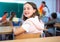 Diligent preteen girl student sitting at school desk during lesson