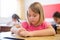 Diligent preteen schoolgirl making notes of teacher lecture