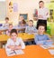 Diligent schoolkids with teacher during lesson in classroom