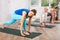 Diligent women practicing lizard pose of yoga in light fitness room