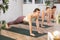 Diligent women practicing plank pose of yoga in light fitness room