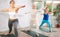 Diligent women practicing warrior pose of yoga in light fitness room