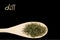 Dill on wooden spoon isolated on black background. Latin name Anethum graveolens